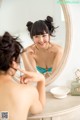 A woman in a blue bikini looking at herself in the mirror.